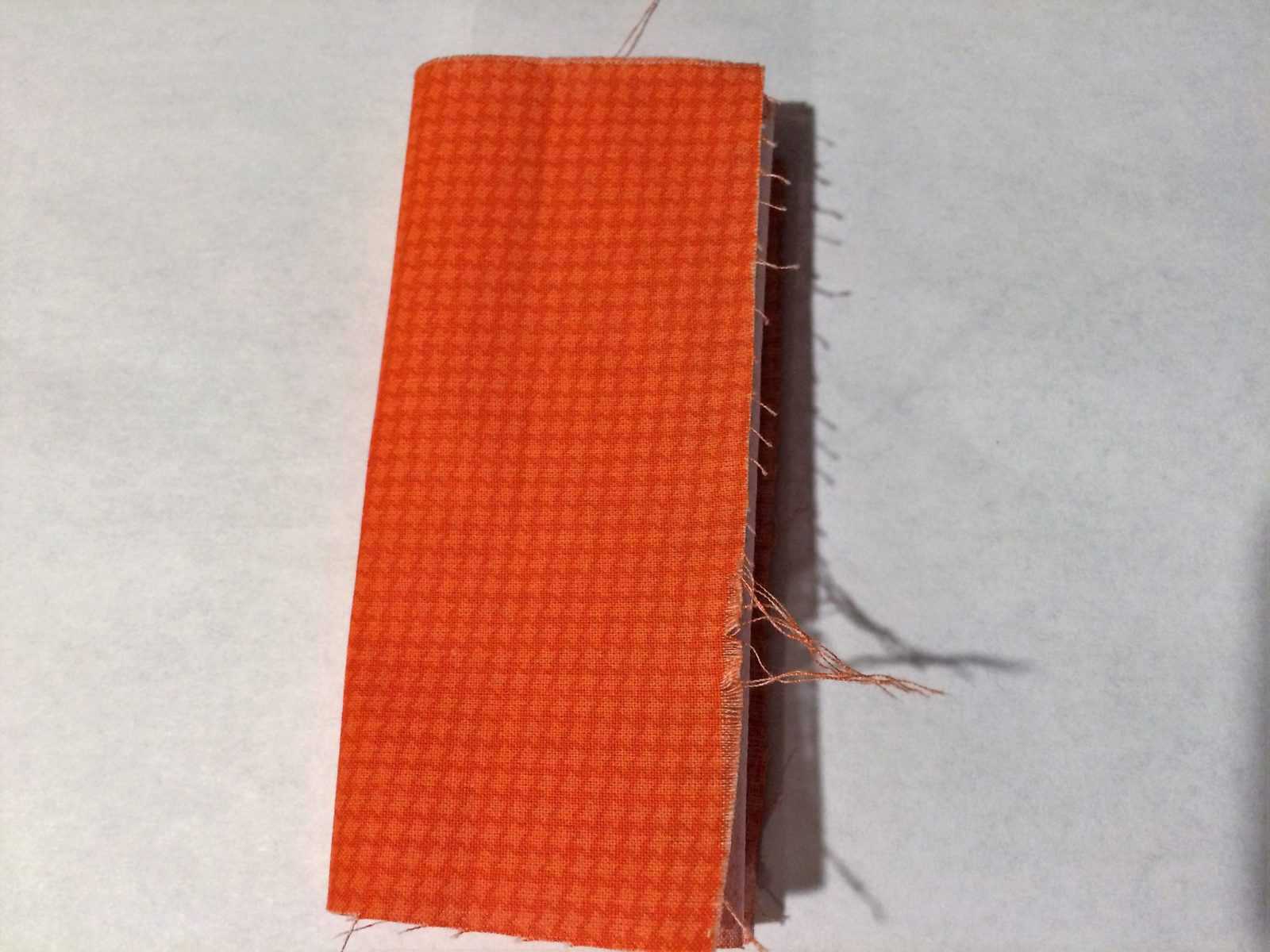 Orange fabric folded into smaller rectangle.