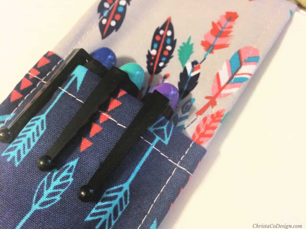 Pen pocket in blue and grey fabric with coral feathers and fountain pens.