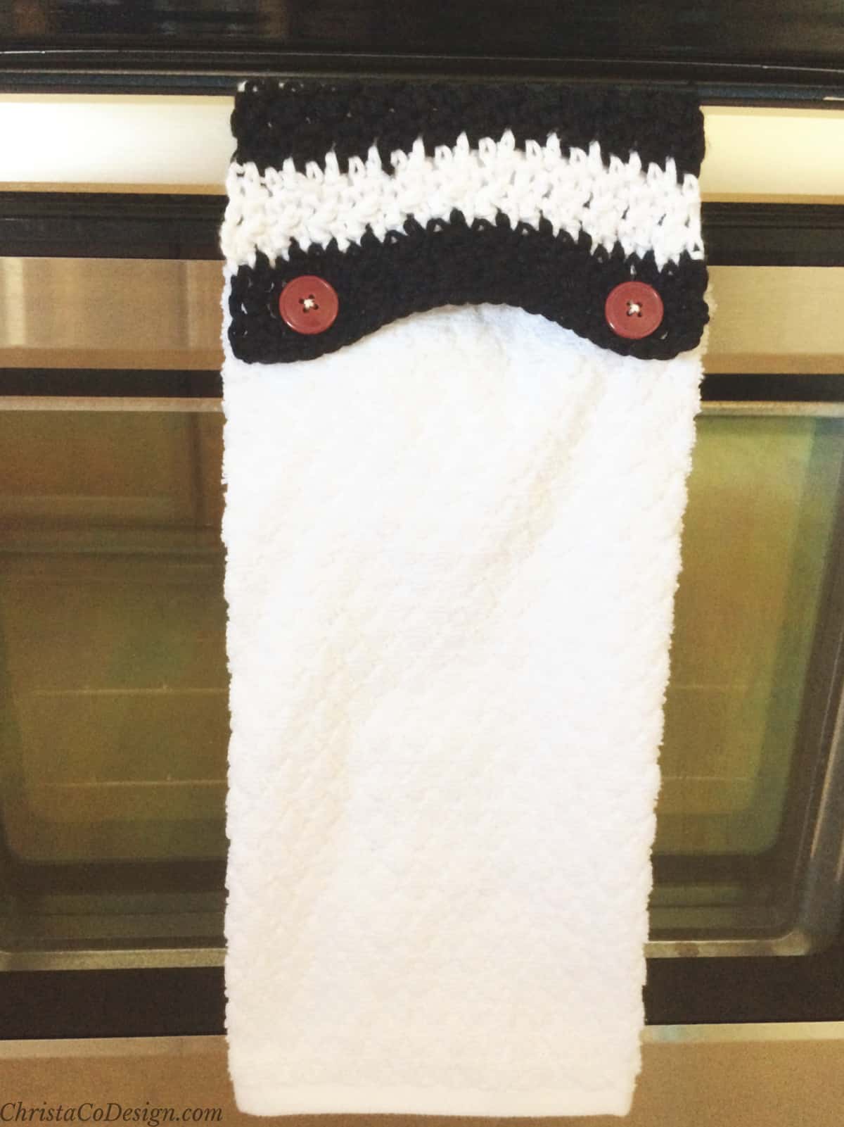 Black and white crochet towel topper hanging on stove.