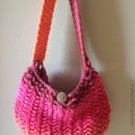 Complete boho bag in pinks hanging on beige wall.