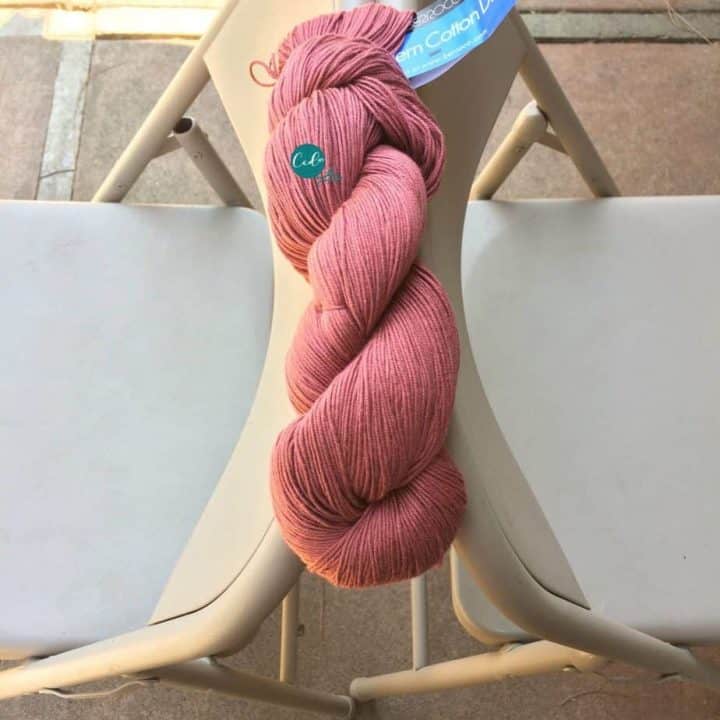 Two chairs back to back with a pink hank of yarn between them.