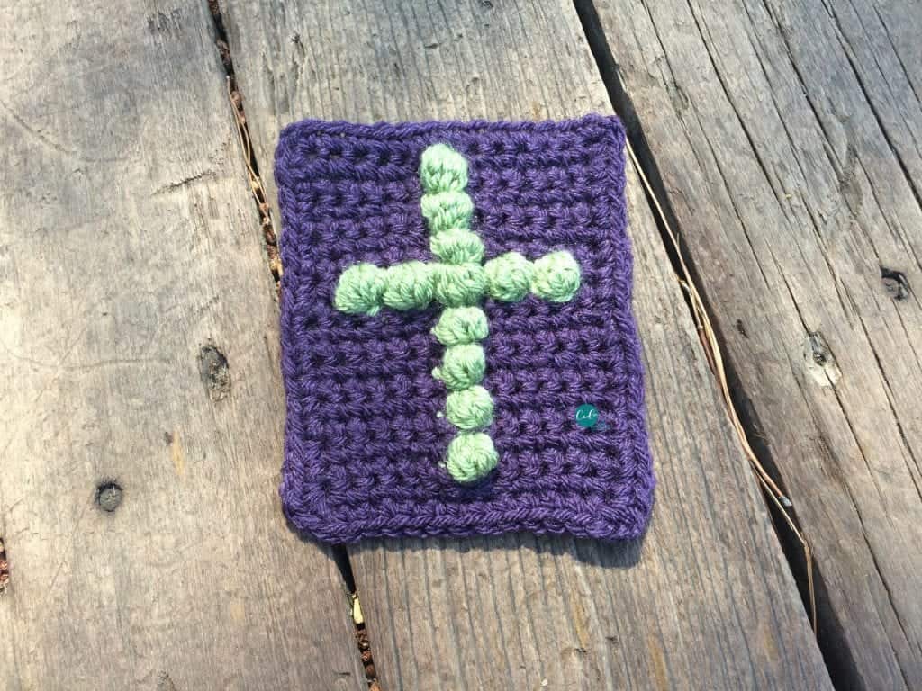 Crochet cross on purple pocket size cloth.