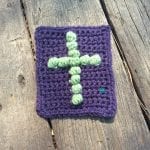 Crochet cross on purple pocket size cloth.
