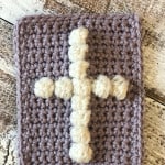 White cross in bobbles on lavender single crochet rectangle.