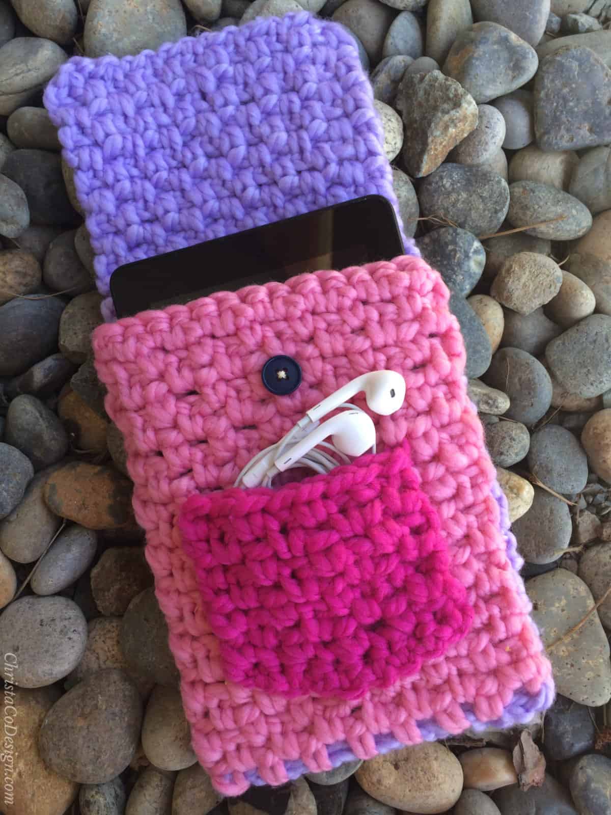 Crochet tablet case open with ear buds in pocket.