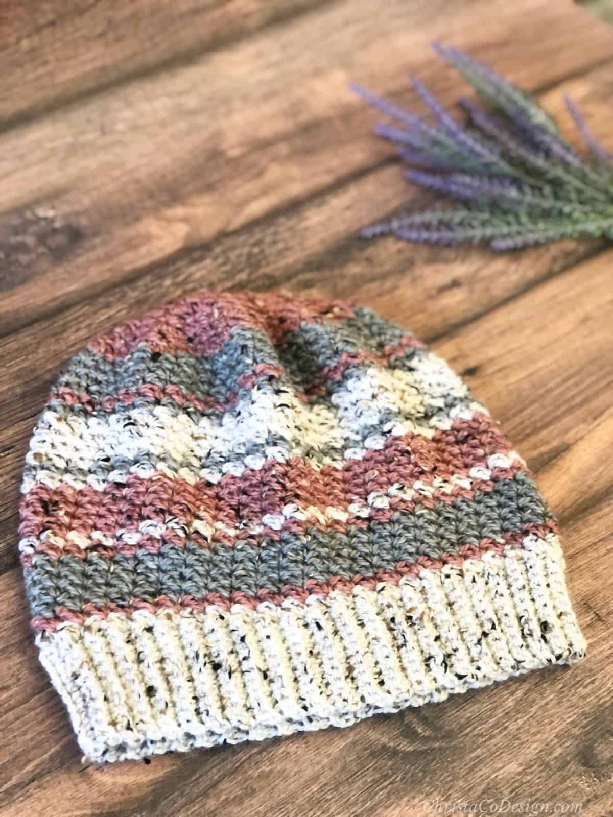 Striped slouchy hat in white, grey and pink laid flat with lavender.