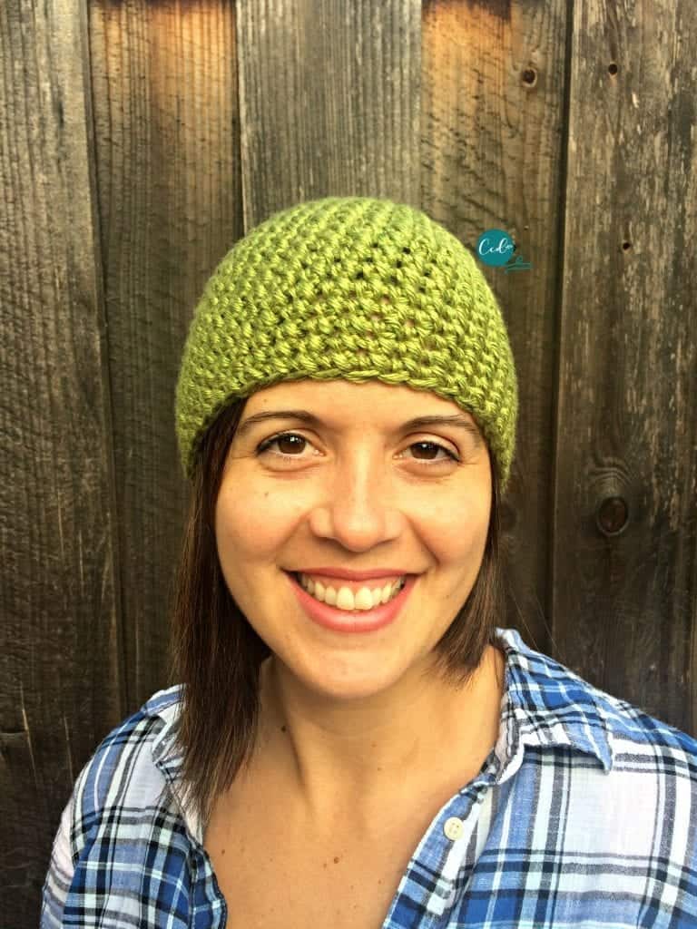 Woman smiling in green mini puff stitch hat.