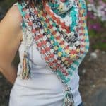 Woman in white with color granny triangle scarf crochet pattern with tassels.