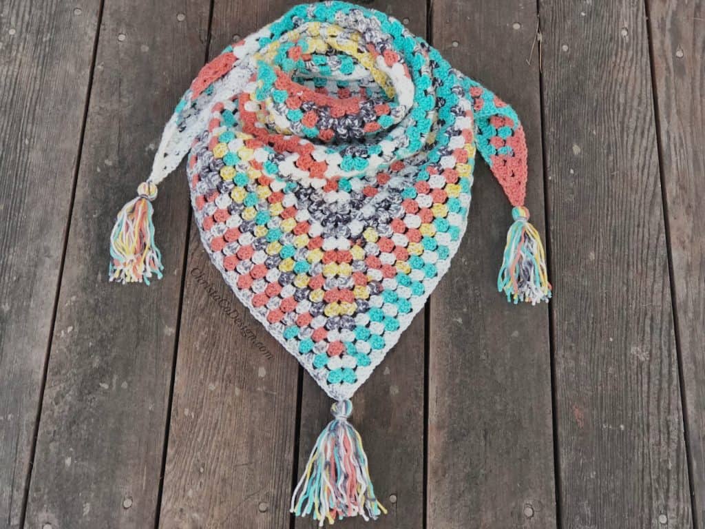 Colorful scarf triangle pattern with tassels crochet on wood back drop.