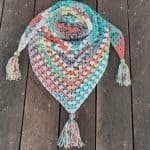 Colorful scarf triangle pattern with tassels crochet on wood back drop.
