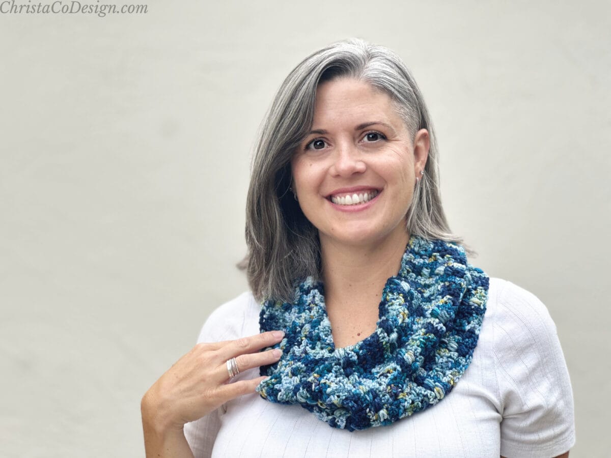 Woman with blue crochet cowl over white shirt.