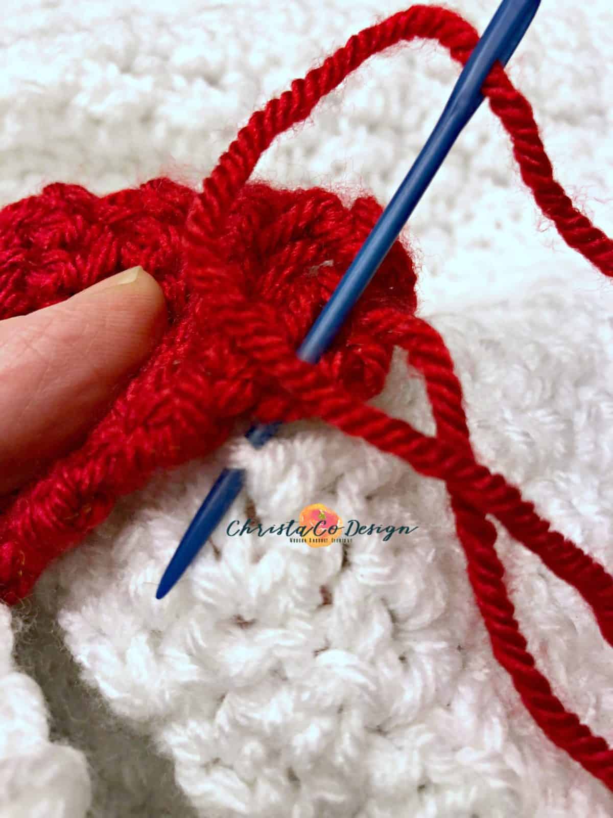 picture of blue yarn needle threaded with red yarn matching the Christmas light to appliqués on to white blanket