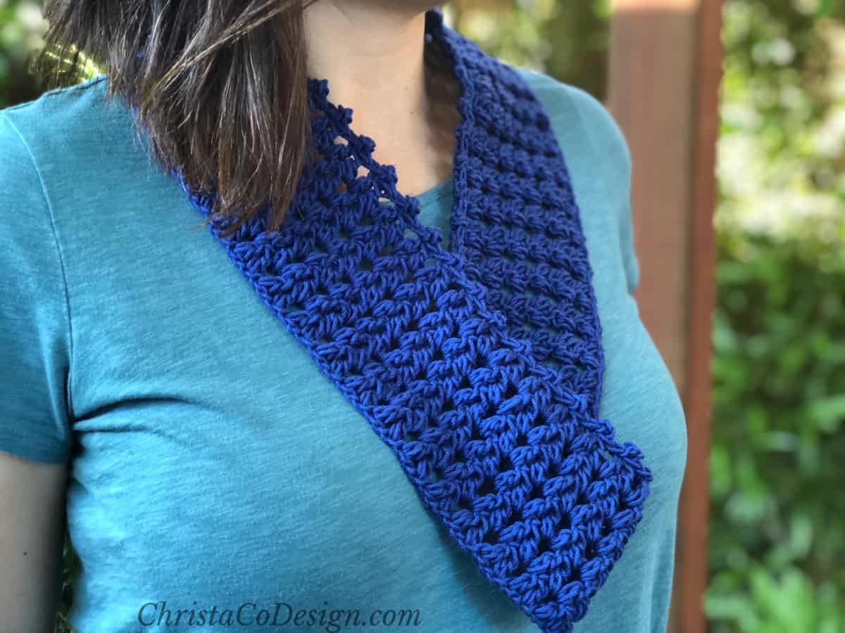 Dark blue crochet infinity scarf on woman's neck.