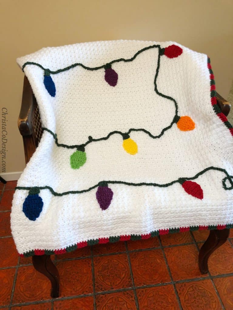 White crochet blanket with color Christmas lights free pattern on chair.
