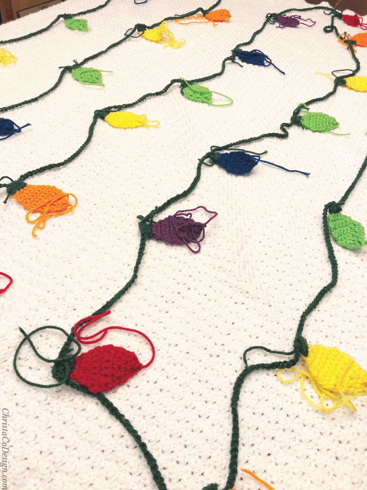 All the crochet Christmas lights laid out on white crochet blanket.