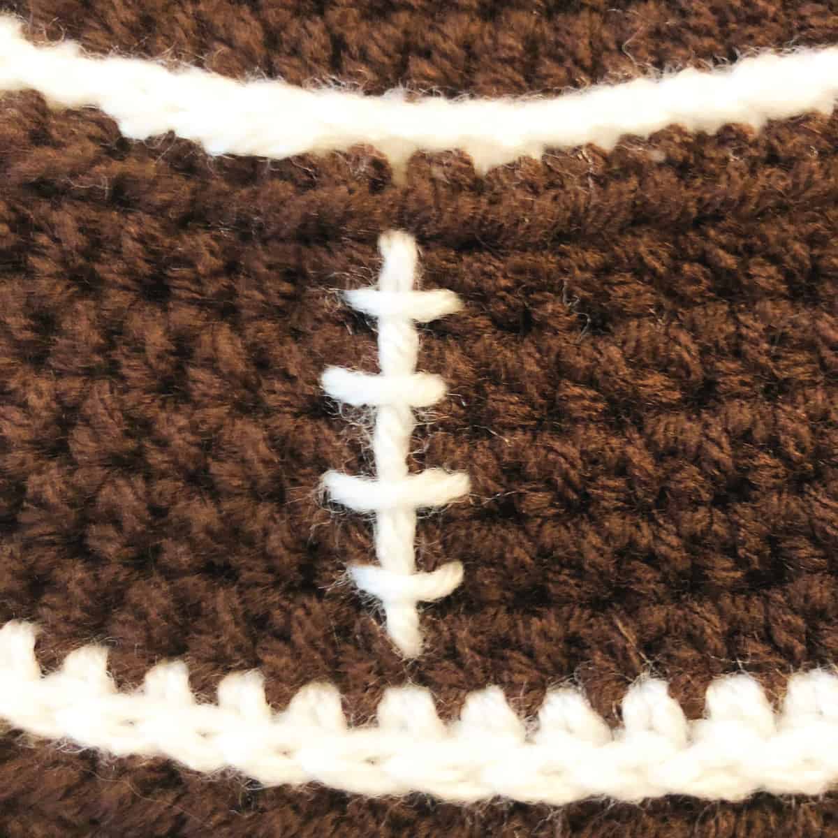 Close up of football laces embroidered on crochet hat.