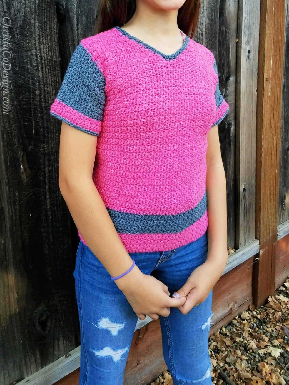 Girl in pink sweater with hands clasped.