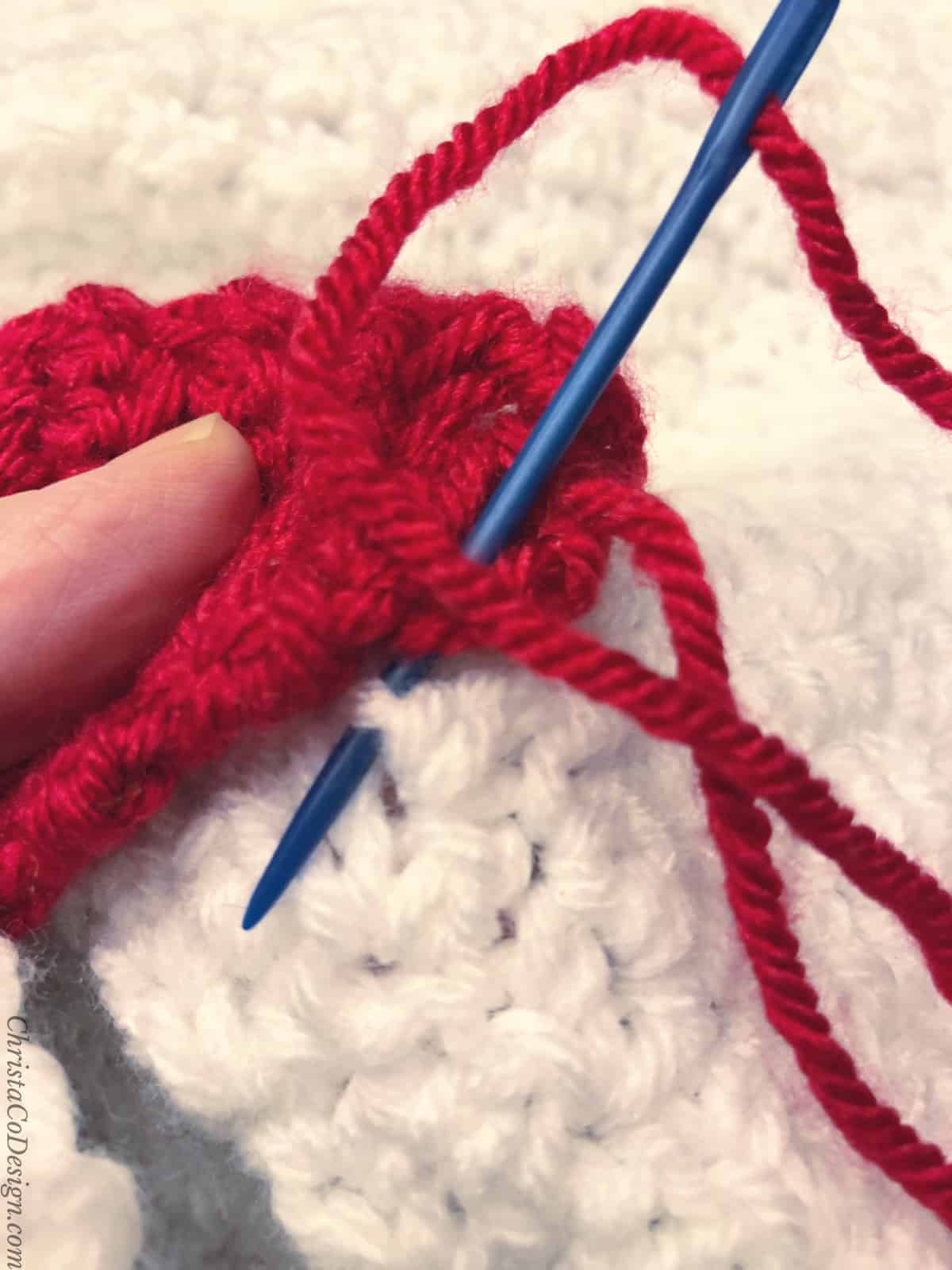 Sew the Christmas lights on to the finished crochet blanket with yarn and needle.
