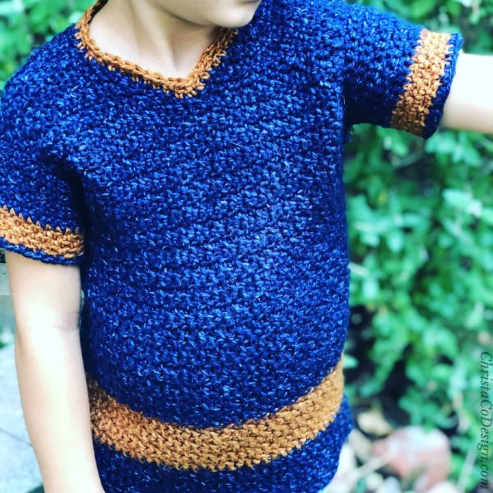 Boy pointing in v-neck sweater of blue trimmed in rust.