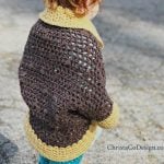 Toddler in brown sweater with gold trimmed sleeves.