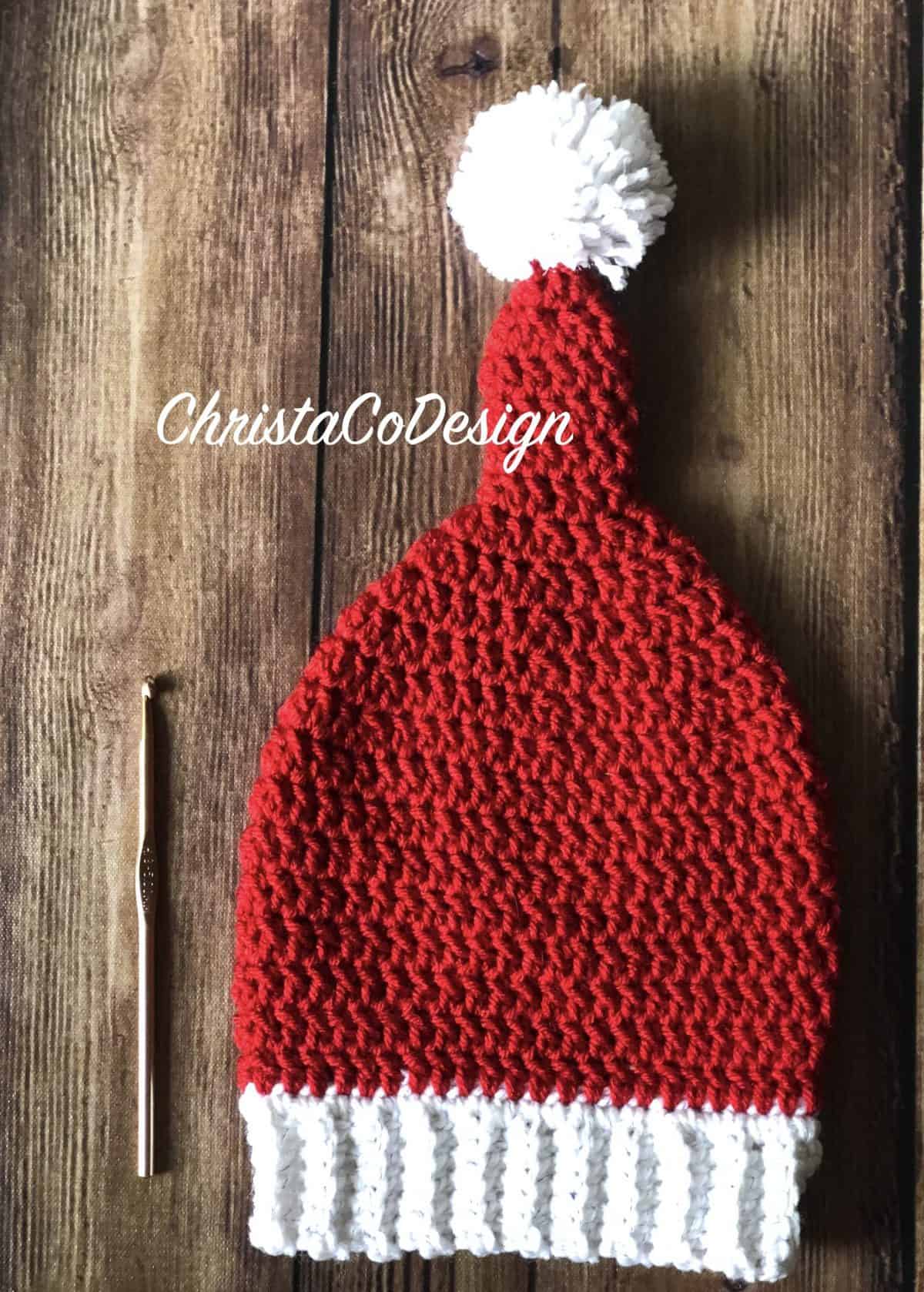 Crochet elf hat in red yarn and white trim with Pom Pom.