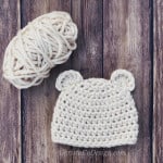 Baby bear chunky crochet beanie flat in cream with yarn ball.