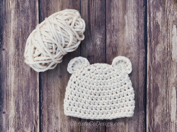 Baby bear chunky crochet beanie flat in cream with yarn ball.