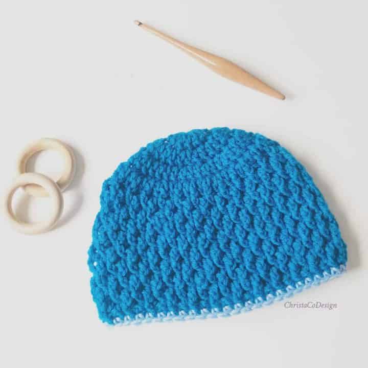 Blue textured hat with wood rings and hook.