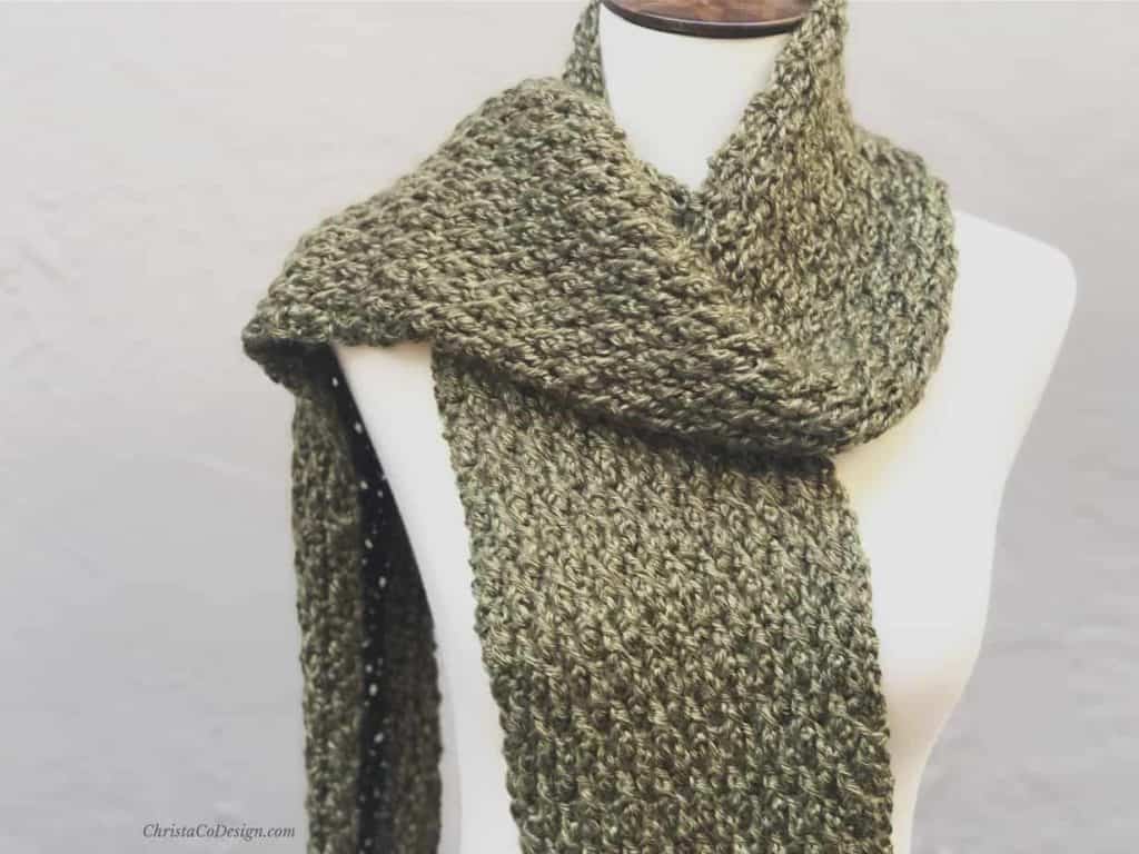 Green textured crochet scarf on mannequin.