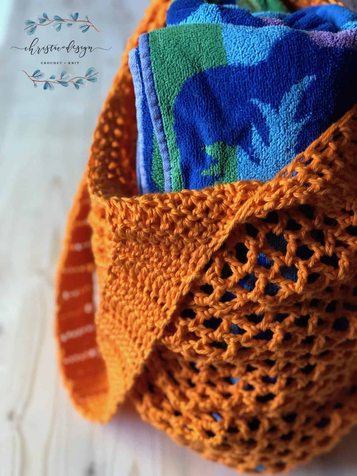 picture of orange crochet market tote bag full of blue beach towel