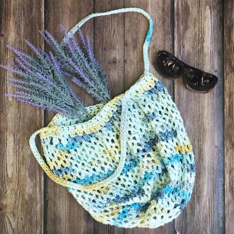 Free crochet tote bag pattern in blue and yellow crochet mesh flat with lavender.