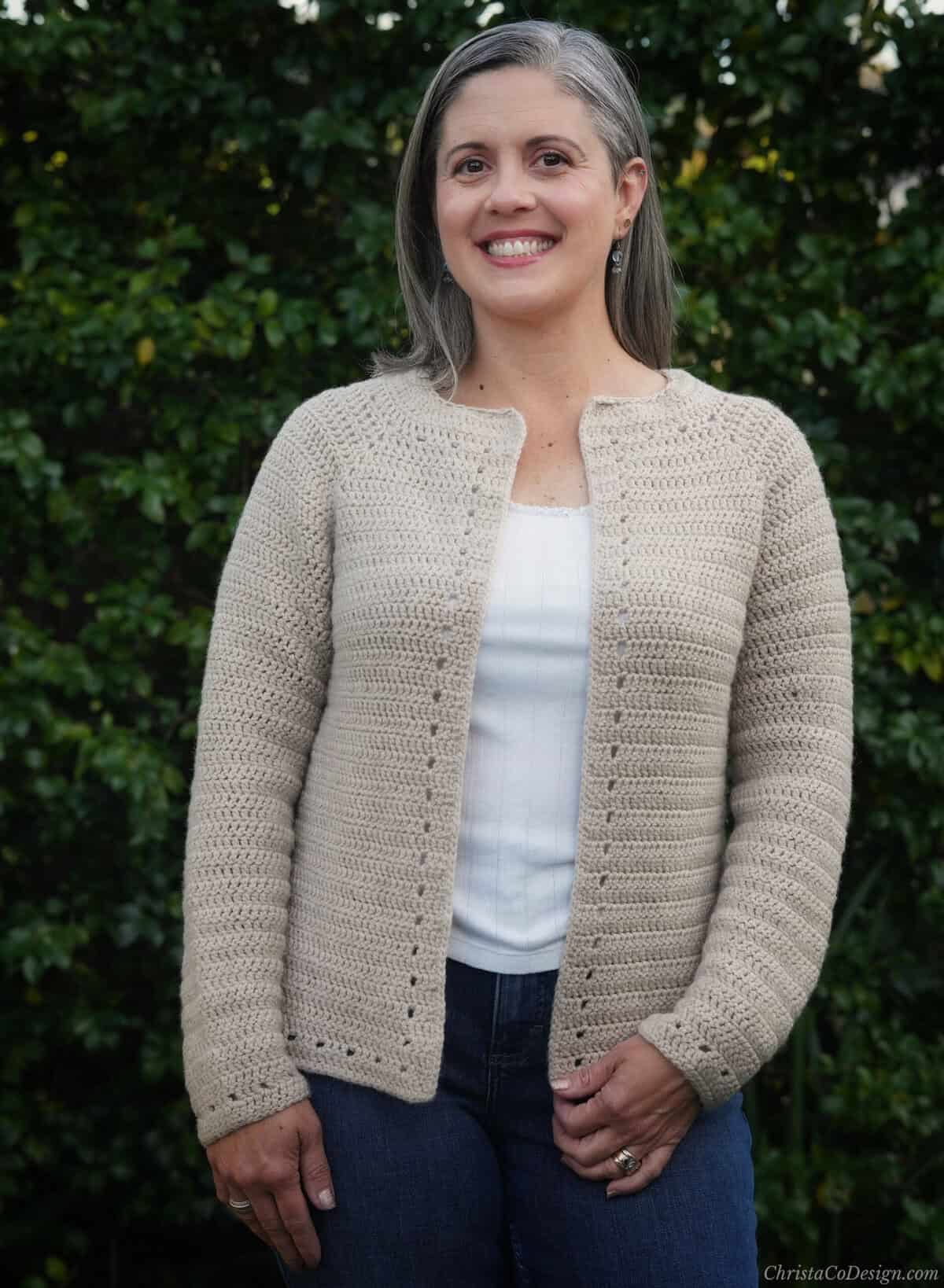 Woman in beige crochet cardigan with eyelet detail.