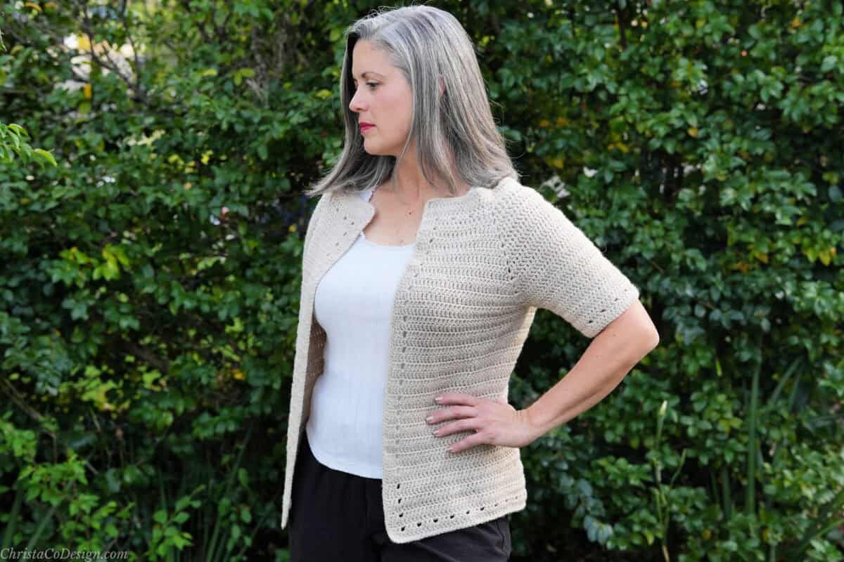 Woman turned to side in short sleeve cardigan.