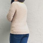 Back view of crochet sweater with hem hat detail on woman facing a away from camera.