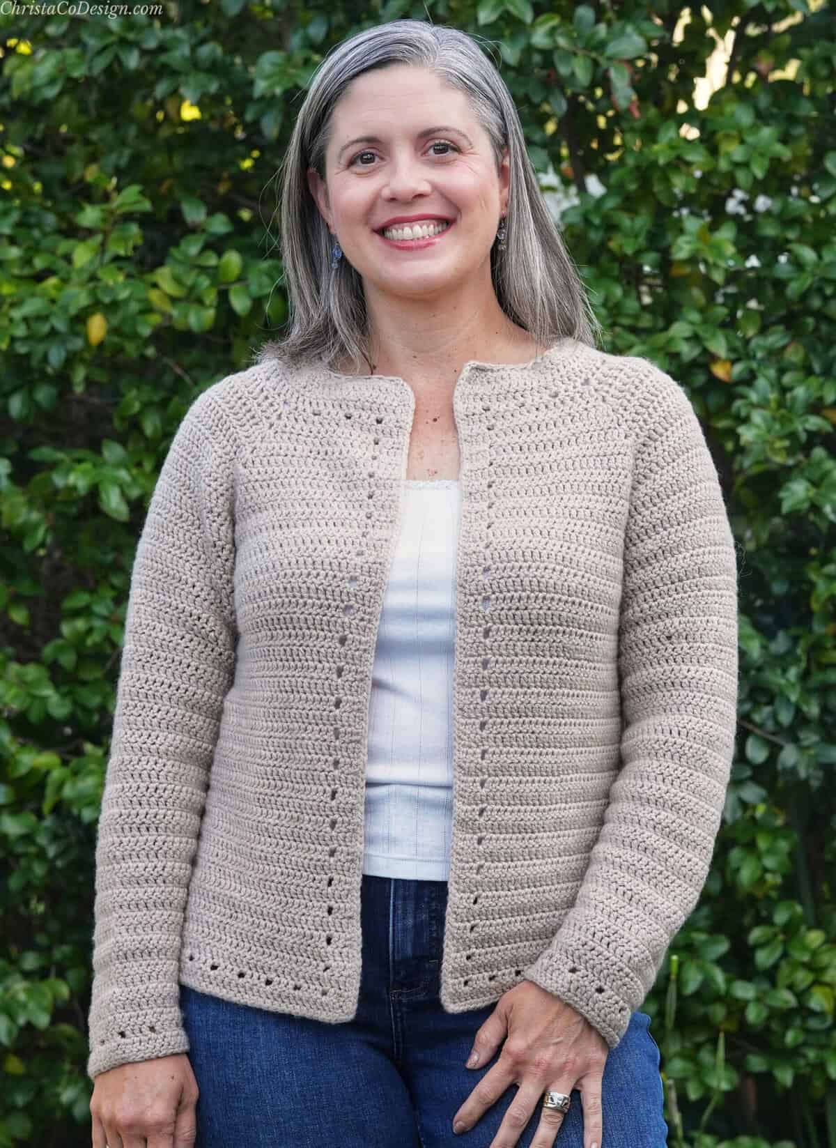 Woman smiling in beige cardigan outside.