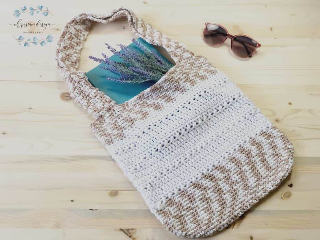 White and beige crochet book bag with notebook and lavender inside.