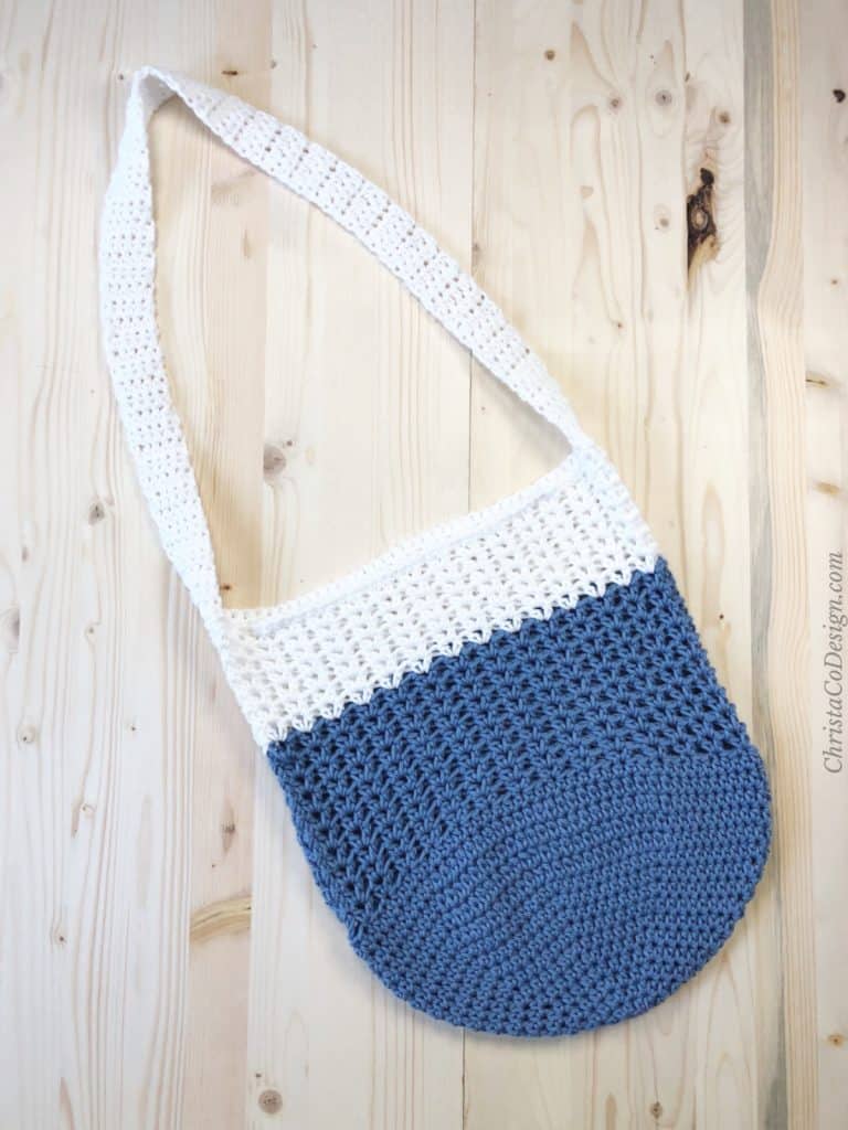 Blue and white crochet market tote bag free pattern on light wood back ground.