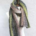 Crochet shawl styled as scarf around mannequin neck.