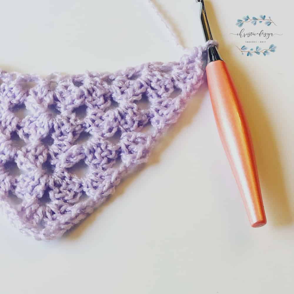 Purple ambra granny stitch triangle scarf with peach crochet hook.