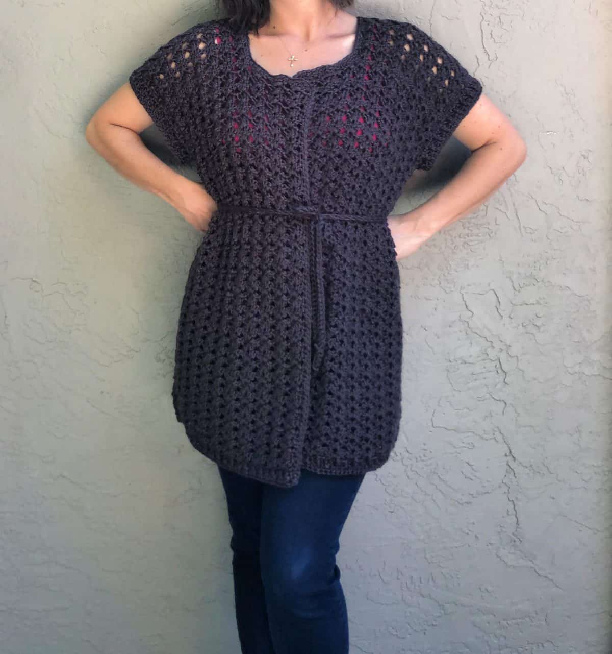 Woman in black crochet cardigan free pattern in short sleeves.