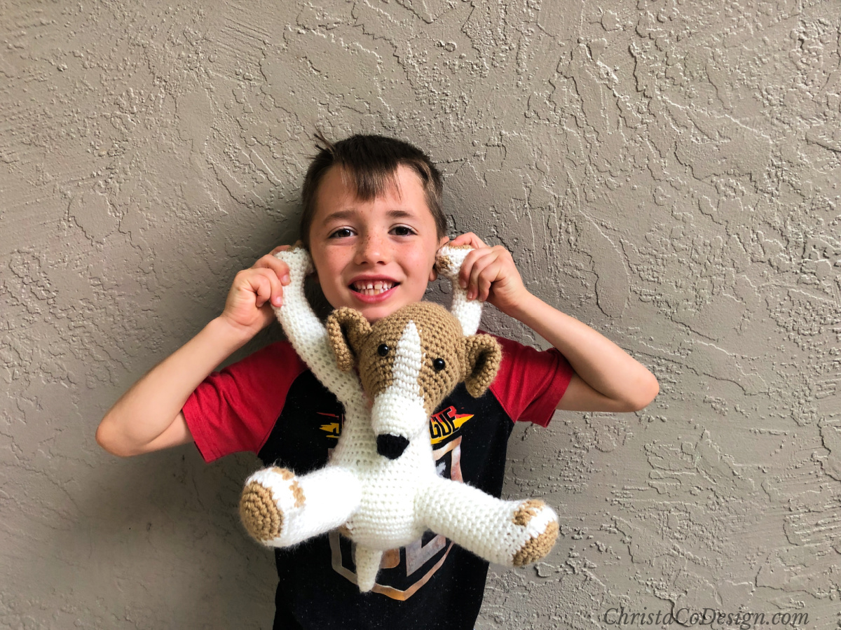 Boy holding crochet puppy.