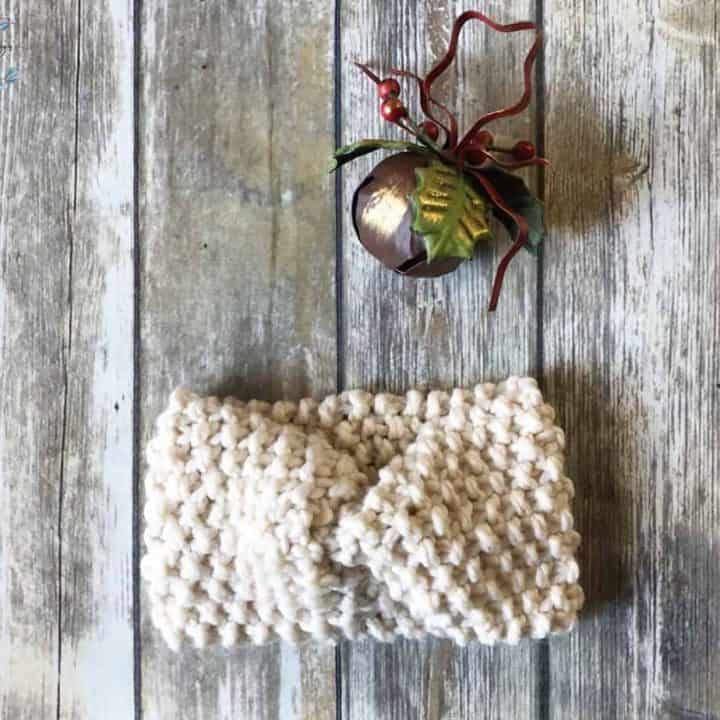 Easy knit ear warmer pattern in chunky cream yarn with Christmas bell