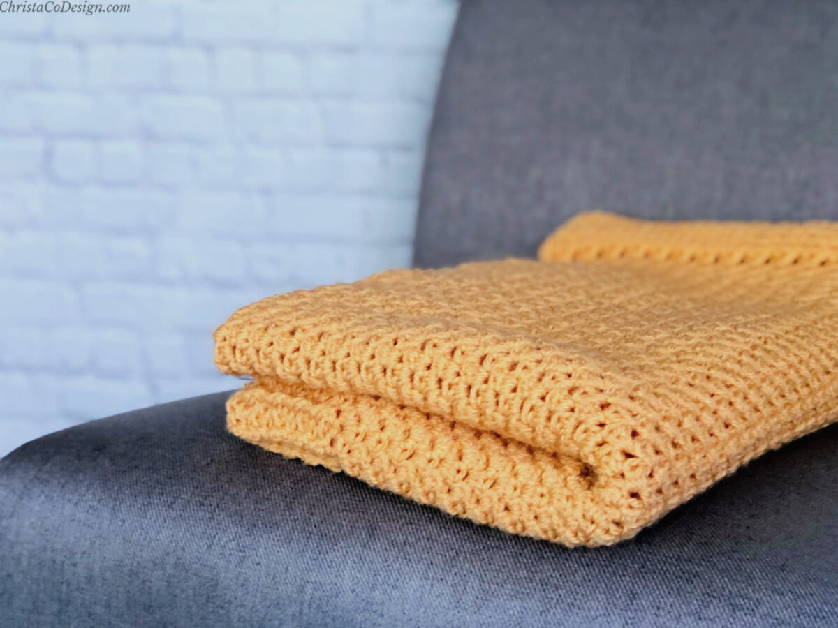 Folded orange blanket on grey chair.