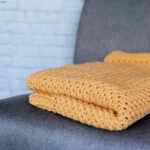 Folded orange blanket on grey chair.