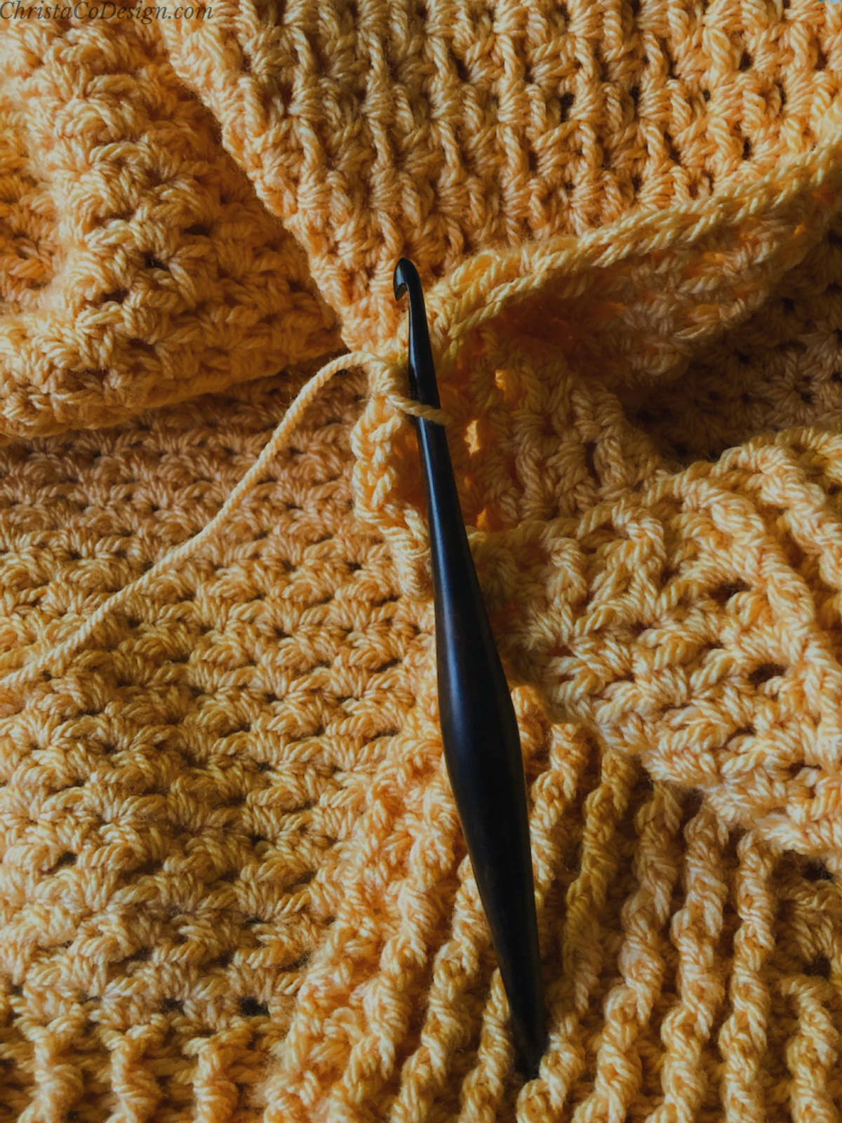 Orange blanket and wood crochet hook.