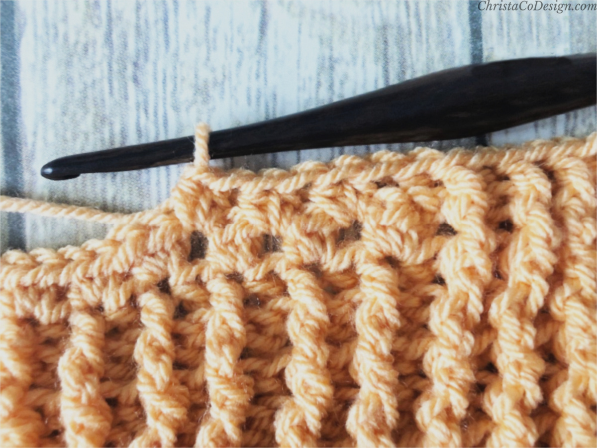 Crochet blanket center stitches in orange on hook.