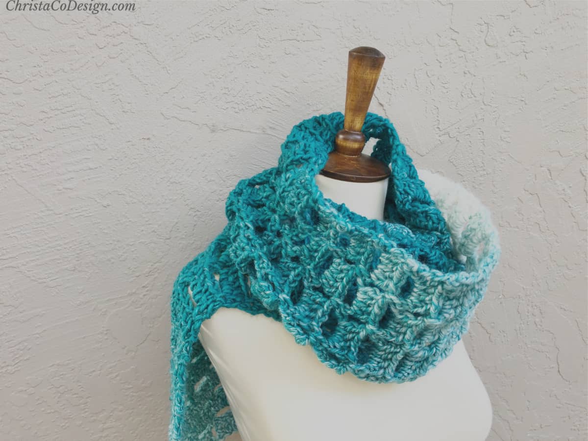 Teal crochet scarf wrapped on mannequin.