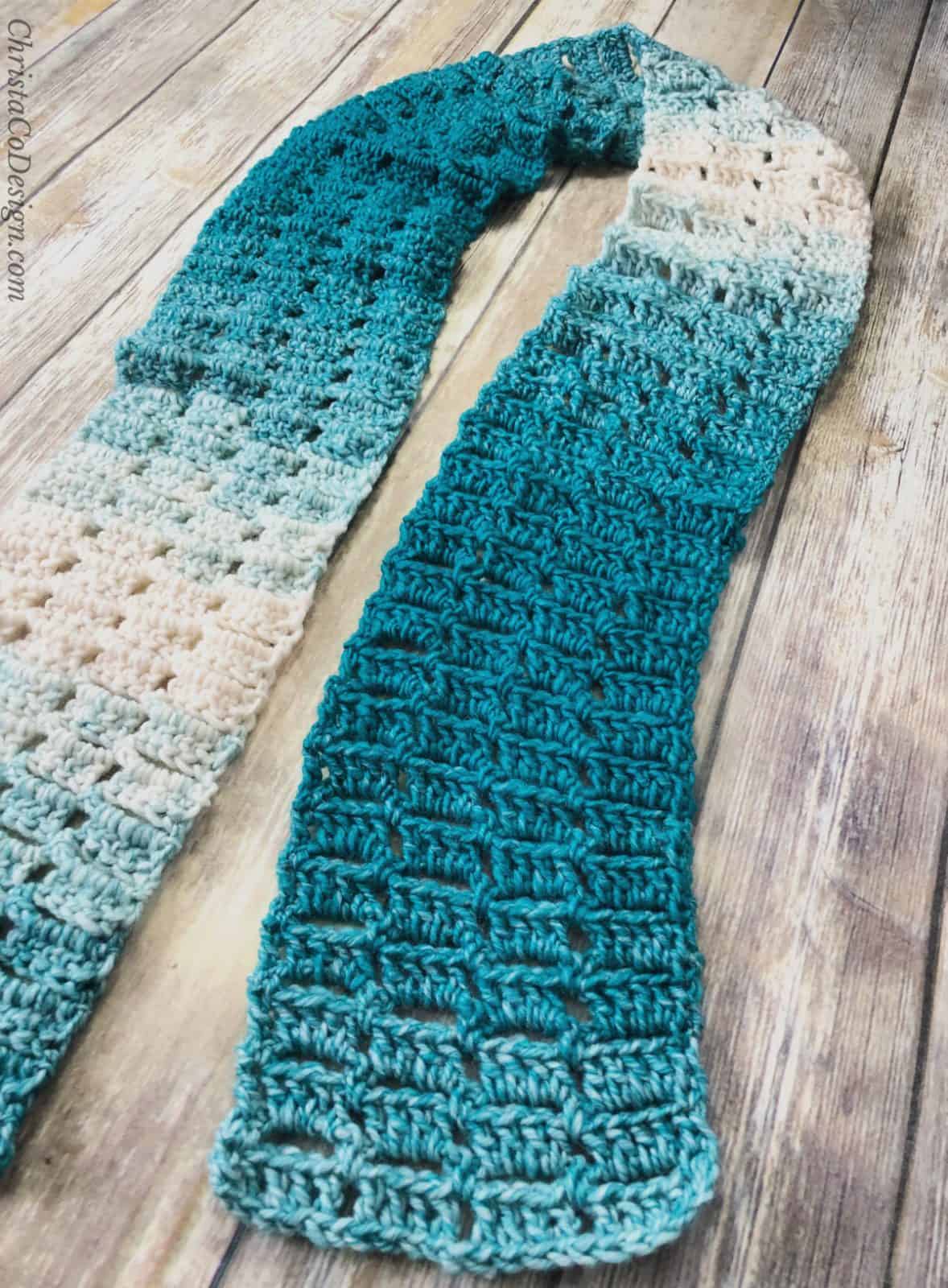 Teal and white crochet scarf laid out in u shape.