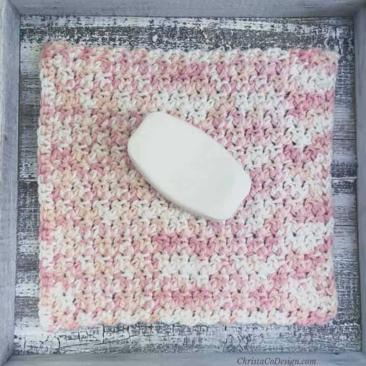Crochet washcloth in pink and white with bar of soap.