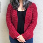 Woman in red crochet cardigan over black shirt with arms crossed in front.
